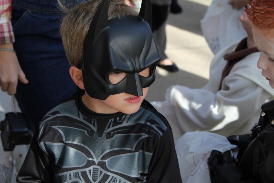 Ein Kind trägt eine Batman-Maske und ein Batman-Shirt.