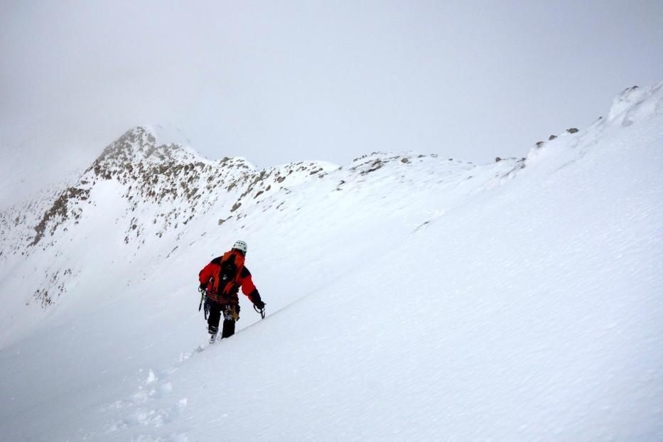 Ein Bergsteiger erklimmt einen schneebedeckten Berg.