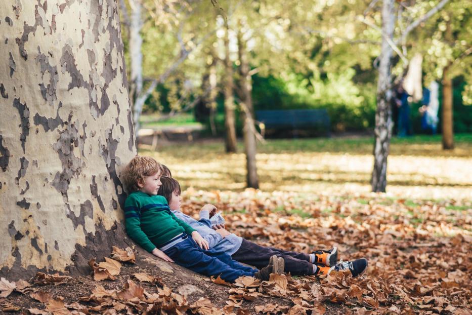 Kinder lehnen an einem Baum.