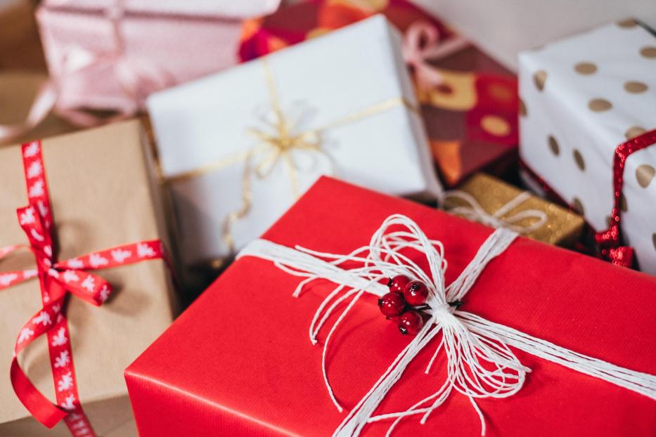 Mehrere verpackte Geschenke mit Schleifen und Bändern liegen übereinander.