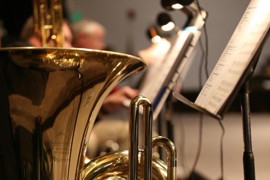 Eine goldene Tuba steht auf einer Bühne vor Notenständern.