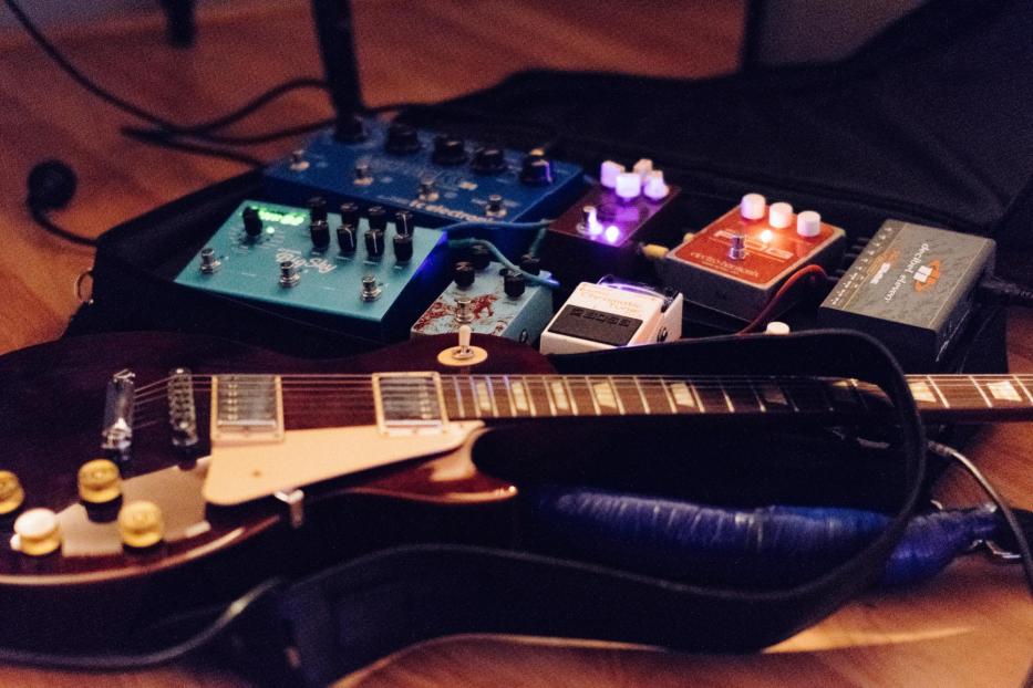 Eine E-Gitarre liegt in einem Gitarrenkoffer, umgeben von Effektpedalen.