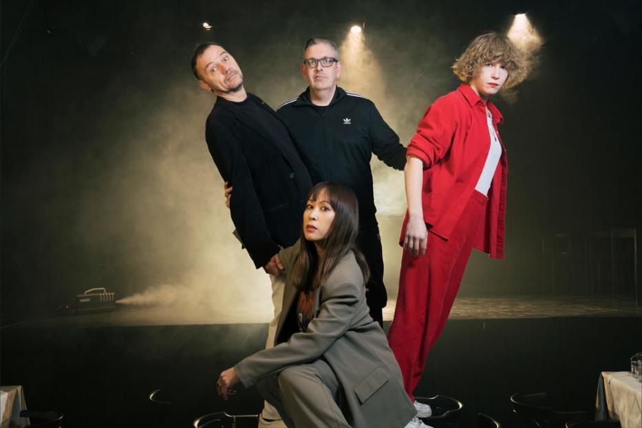 Die Band International Teachers of Pop posiert auf einer Bühne mit Nebel im Hintergrund.