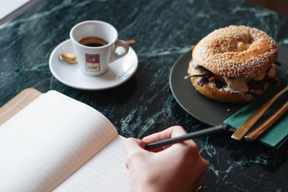 Ein Kaffee und ein Bagel auf einem Tisch platziert.