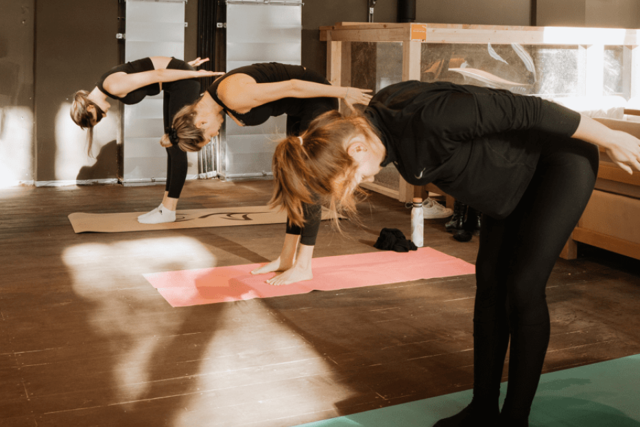 Drei Frauen beugen sich während einer Yoga-Sitzung nach vorne.