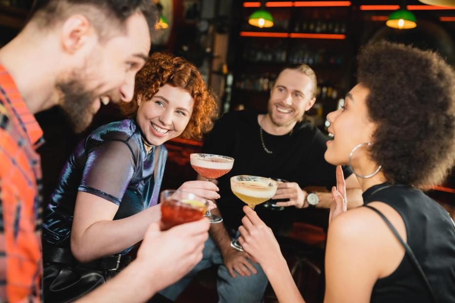 Eine Gruppe von Freunden stößt in einer Bar mit Cocktails an.