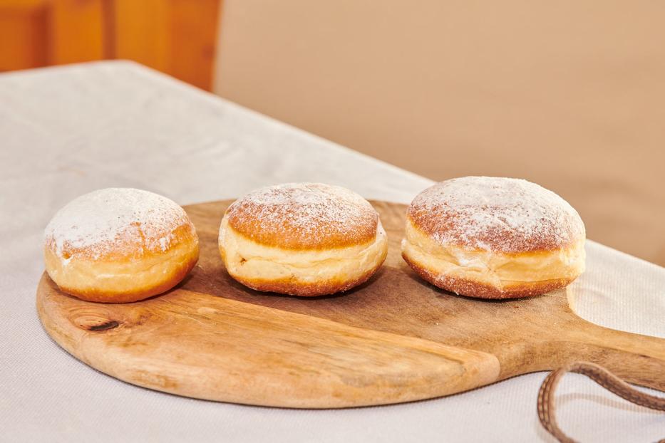 Drei Krapfen einer Reihe auf einer Holzplatte