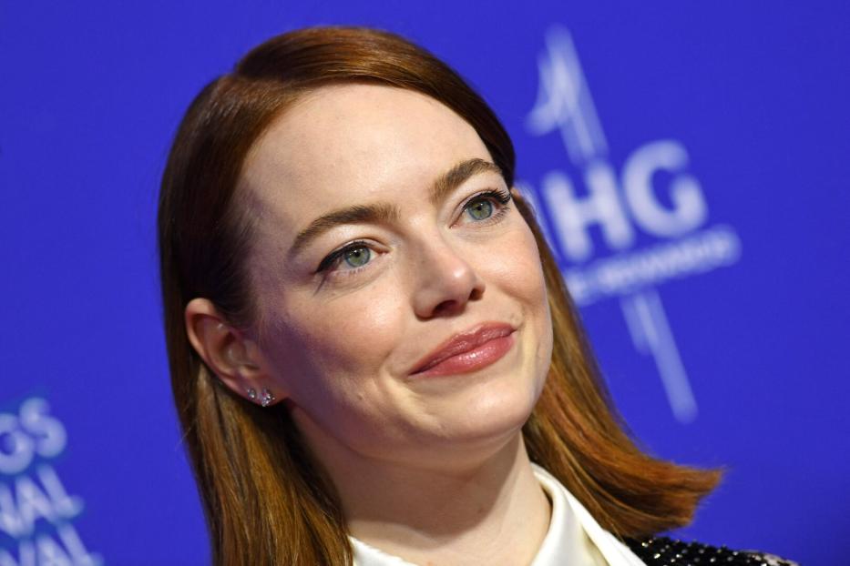 Emma Stone lächelt vor einem blauen Hintergrund.