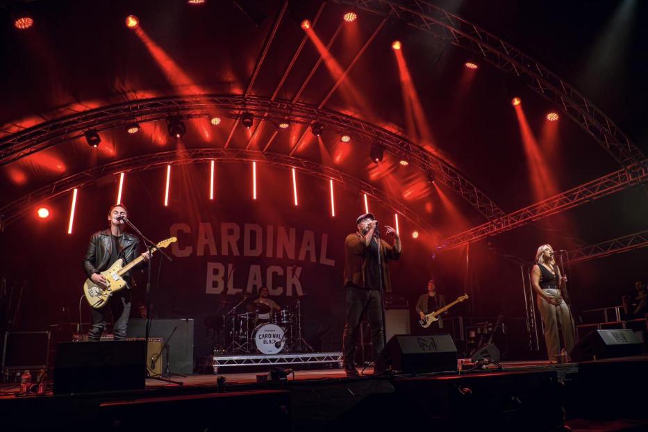 Die Band Cardinal Black tritt auf einer Bühne mit roter Beleuchtung auf.