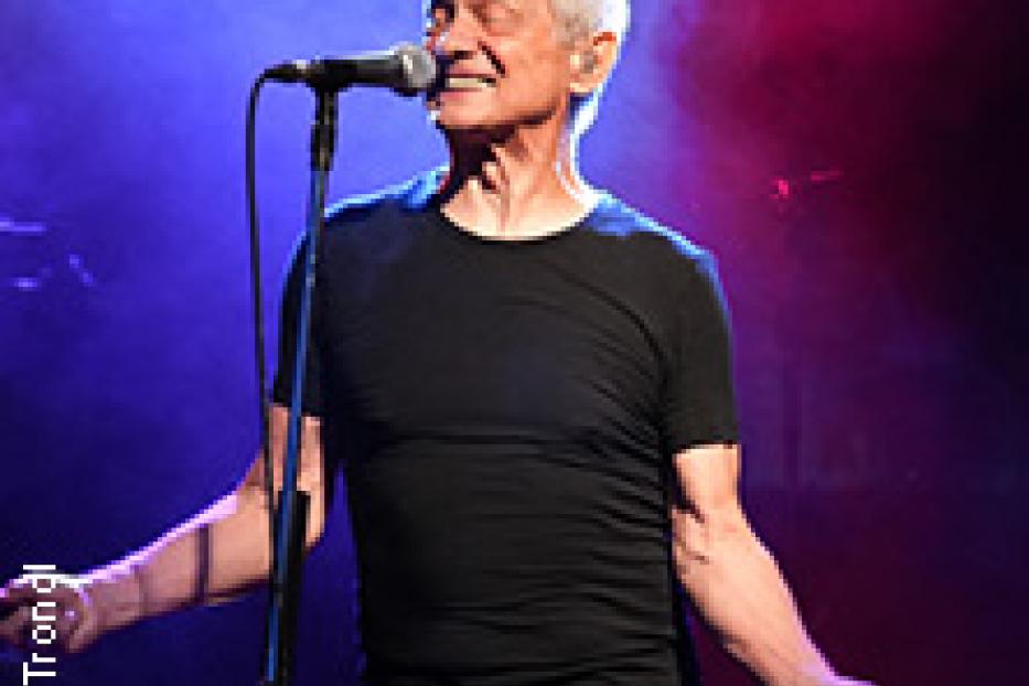 Ein älterer Mann mit Mikrofon singt auf einer Bühne.