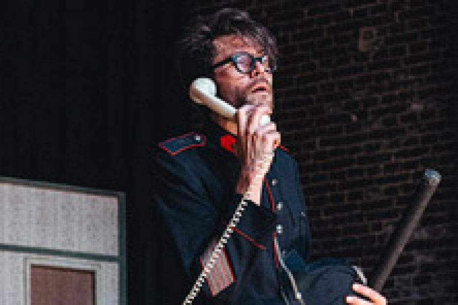 Ein Mann in Uniform telefoniert mit einem alten Telefonhörer.