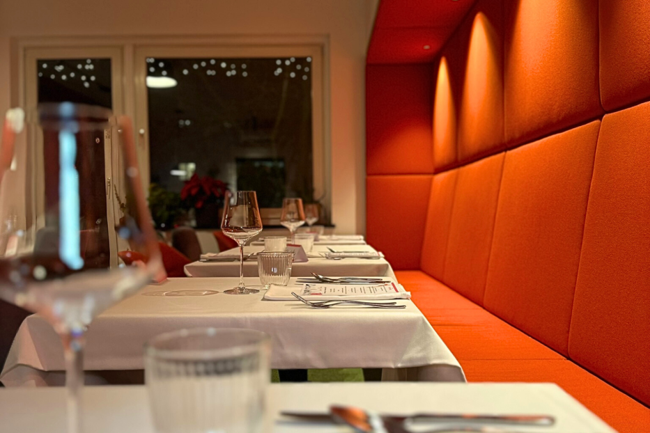Ein gedeckter Tisch in einem Restaurant mit orangefarbener Sitzbank.
