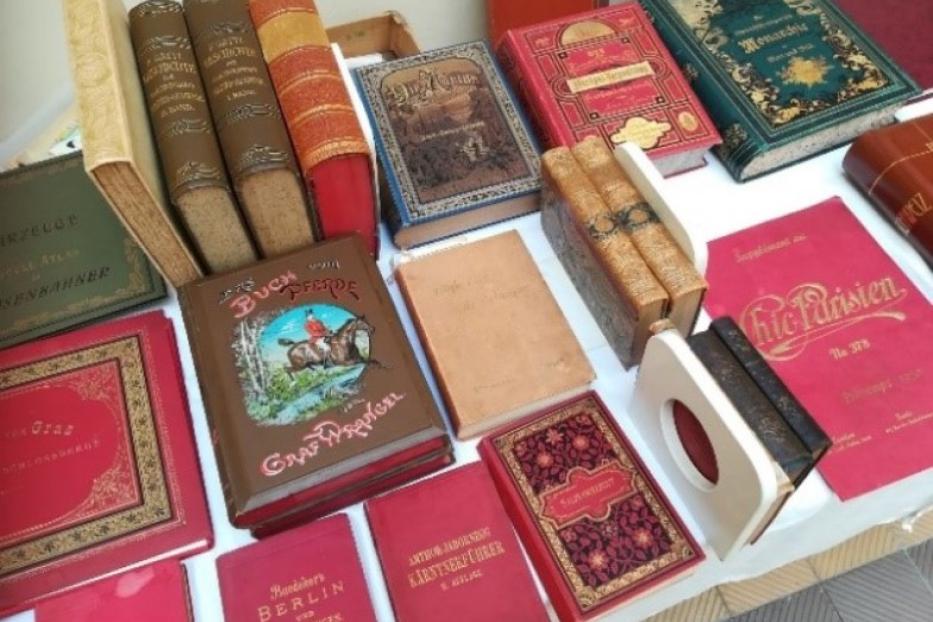 Eine Sammlung alter, gebundener Bücher unterschiedlicher Größe und Farbe liegt auf einem Tisch.