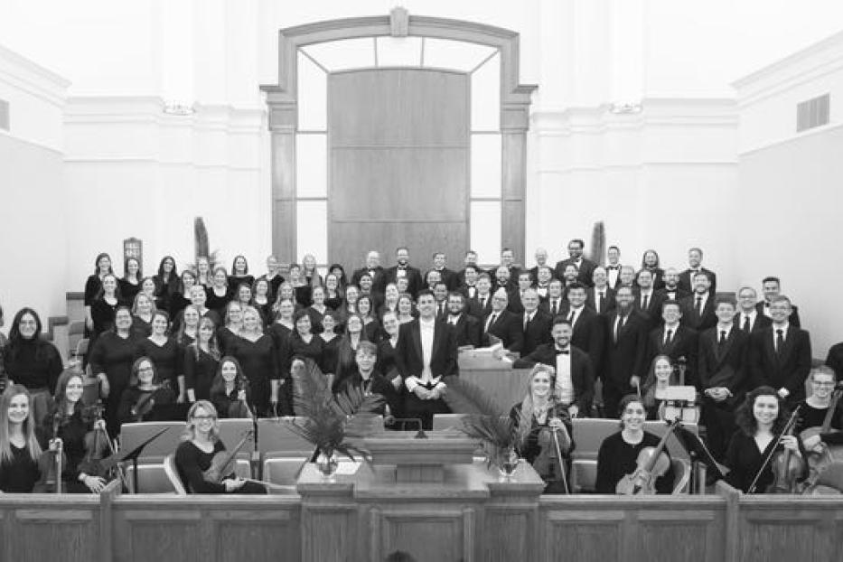 Ein großer Chor und ein Orchester stehen in einer Kirche für ein Gruppenfoto bereit.