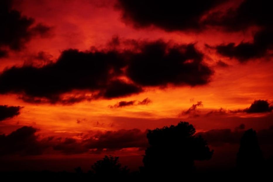 Ein dramatischer Sonnenuntergang mit roten und orangefarbenen Wolken.