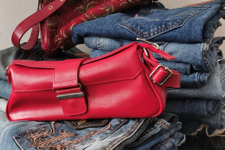Ein Stapel Jeans mit zwei roten Handtaschen darauf.
