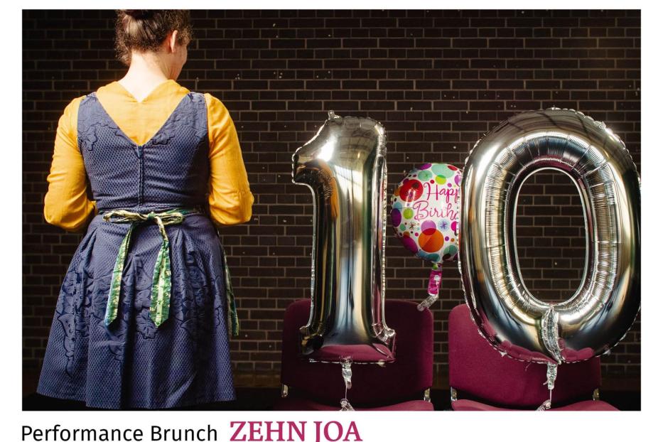 Eine Frau steht vor zwei Stühlen mit silbernen „10“-Ballons und einem Geburtstagsballon.