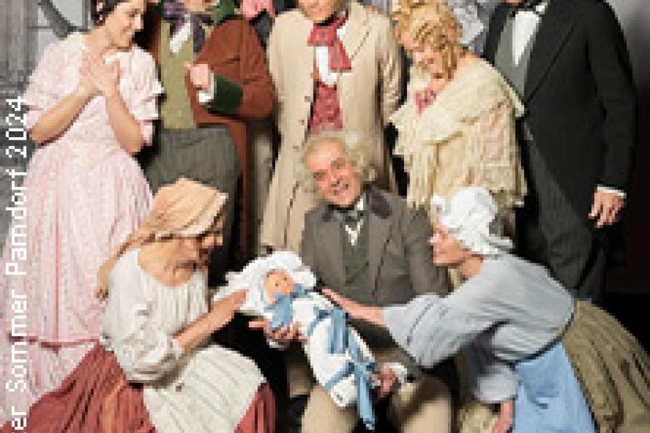Eine Gruppe von Schauspielern in Kostümen umringt ein Baby auf einer Theaterbühne.