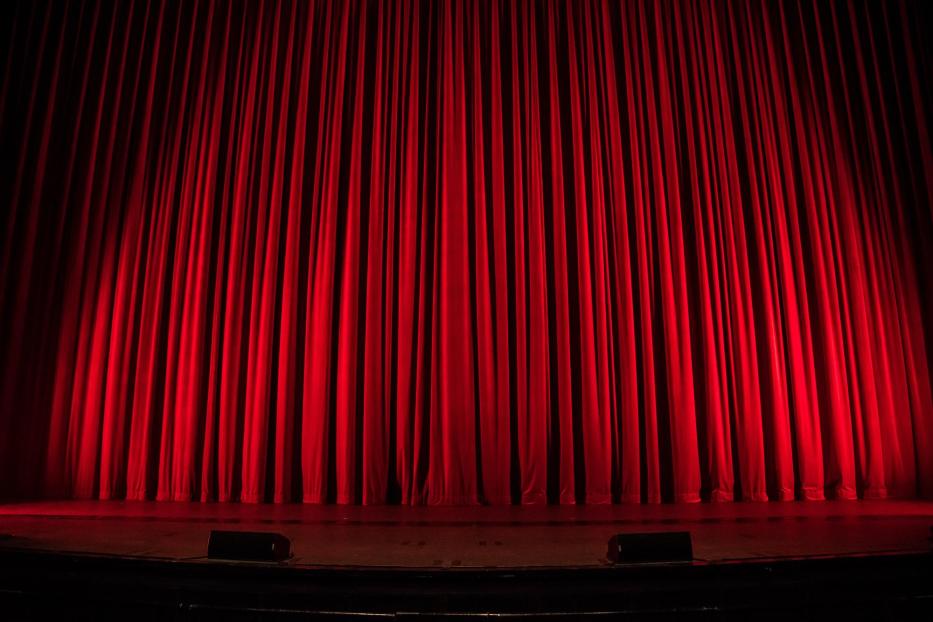 Ein roter Theatervorhang auf einer dunklen Bühne.