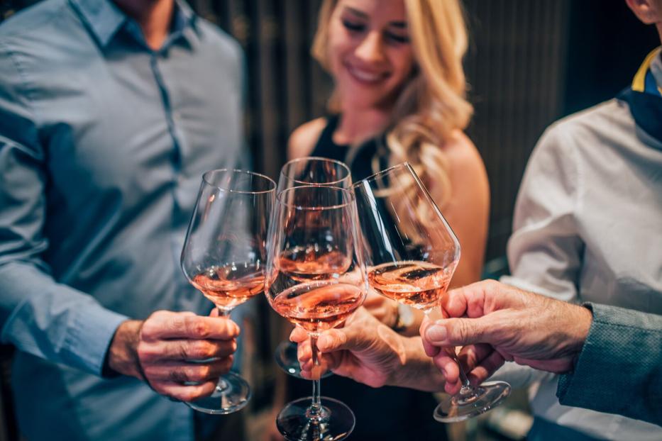Vier Personen stoßen mit Rosé-Schaumwein an