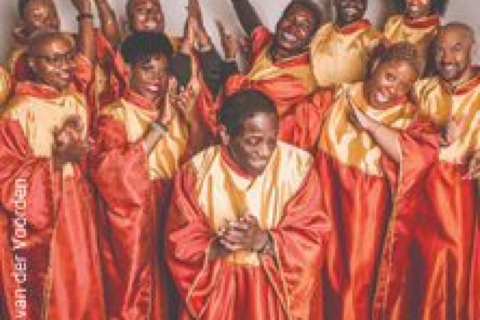 Ein Gospelchor in roten und goldenen Gewändern singt und klatscht in die Hände.