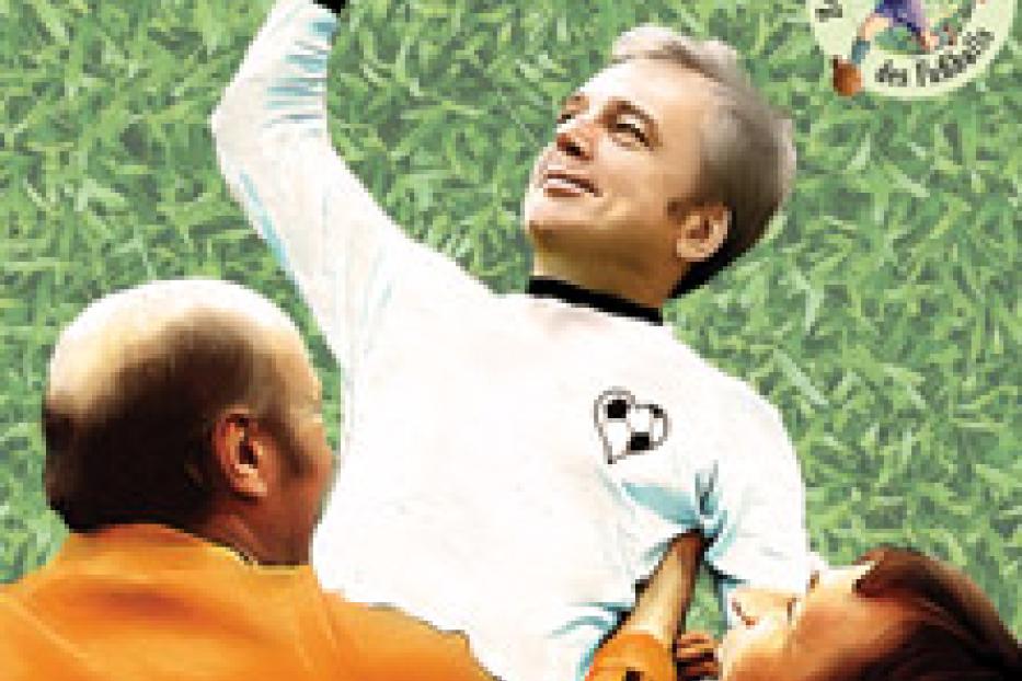Ein älterer Mann im Fußballtrikot wird von zwei Personen gefeiert.