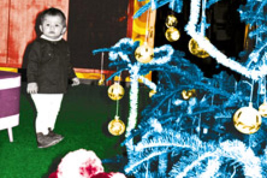 Ein kleines Kind steht neben einem geschmückten Weihnachtsbaum.