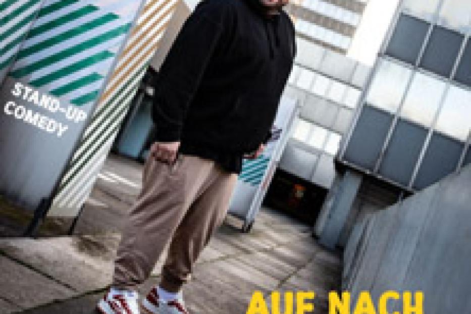 Ein Comedian steht vor einem Gebäude, beworben wird seine Show „Auf nach Bora Bora“.