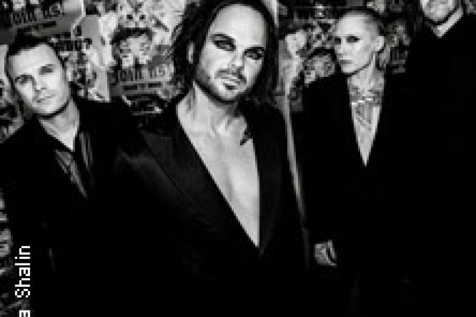 Schwarz-Weiß-Foto der Band Placebo vor einer Wand mit Postern.