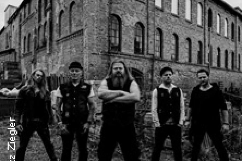 Eine Band posiert vor einem alten Backsteingebäude.