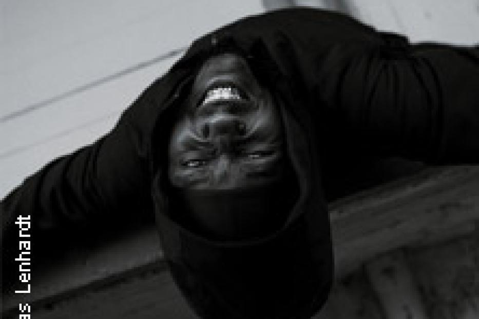 Ein lächelnder Mann mit Kapuze, von unten aufgenommen.