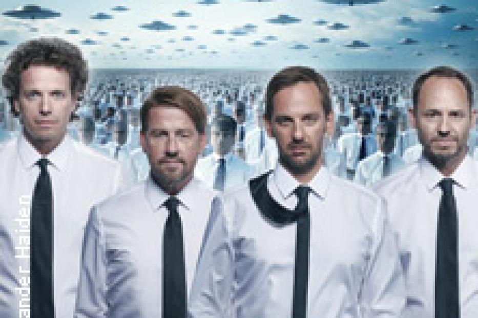 Eine Gruppe Männer in Hemden und Krawatten steht vor einer Menschenmenge und fliegenden Untertassen.