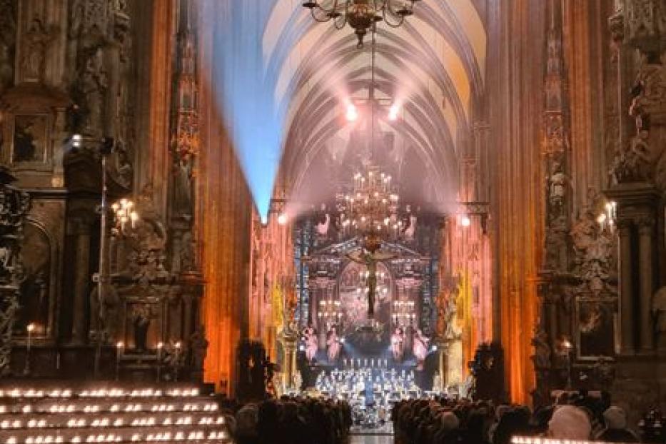 Eine Menschenmenge in einer Kirche, beleuchtet von Kerzen und Scheinwerfern.