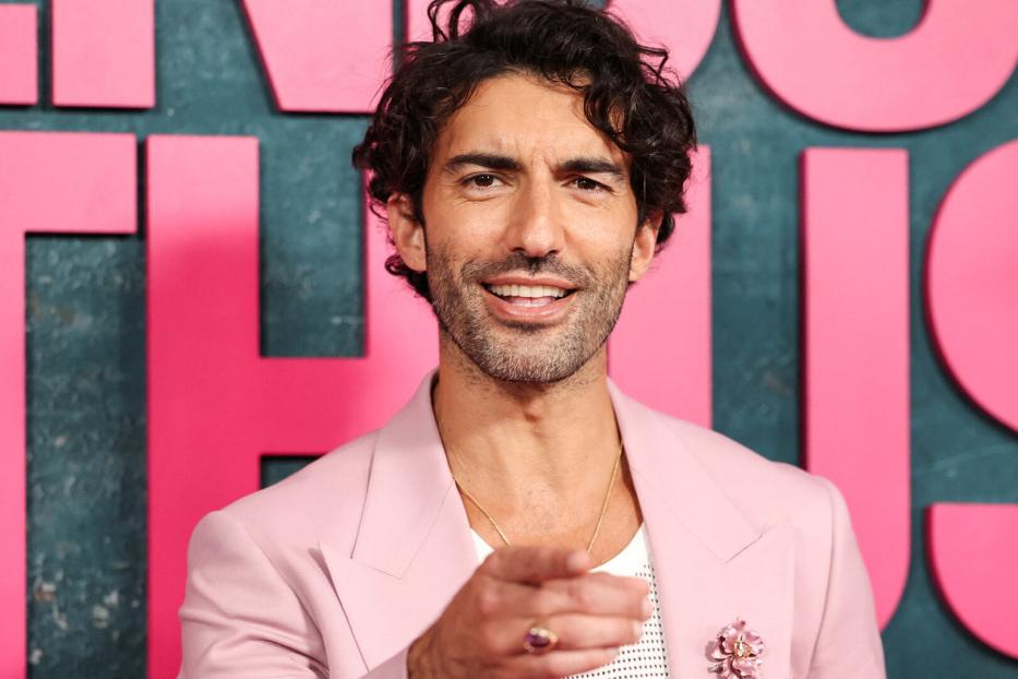 Justin Baldoni lächelt und zeigt mit dem Finger auf den Betrachter.