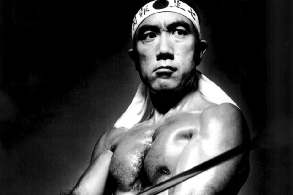 Yukio Mishima  in der Rolle eines idealisierten japanischen Kriegers, der das Stirnband eines Kamikaze trägt und ein Schwert schwingt