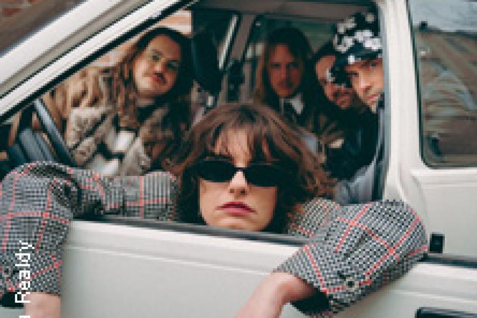 Eine Gruppe von Personen sitzt in einem weißen Auto und posiert für ein Foto.