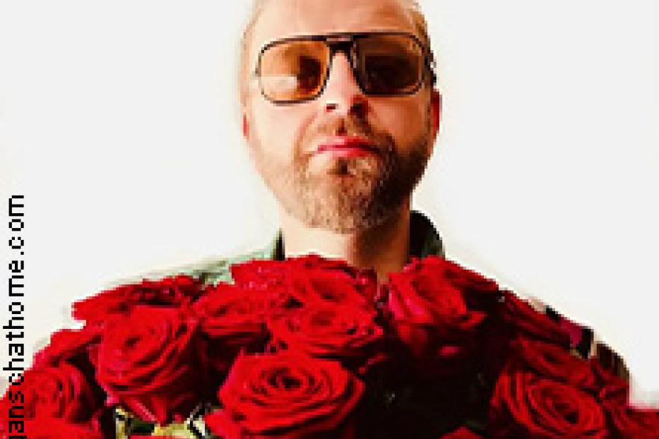 Ein Mann mit Sonnenbrille hält einen großen Strauß roter Rosen.