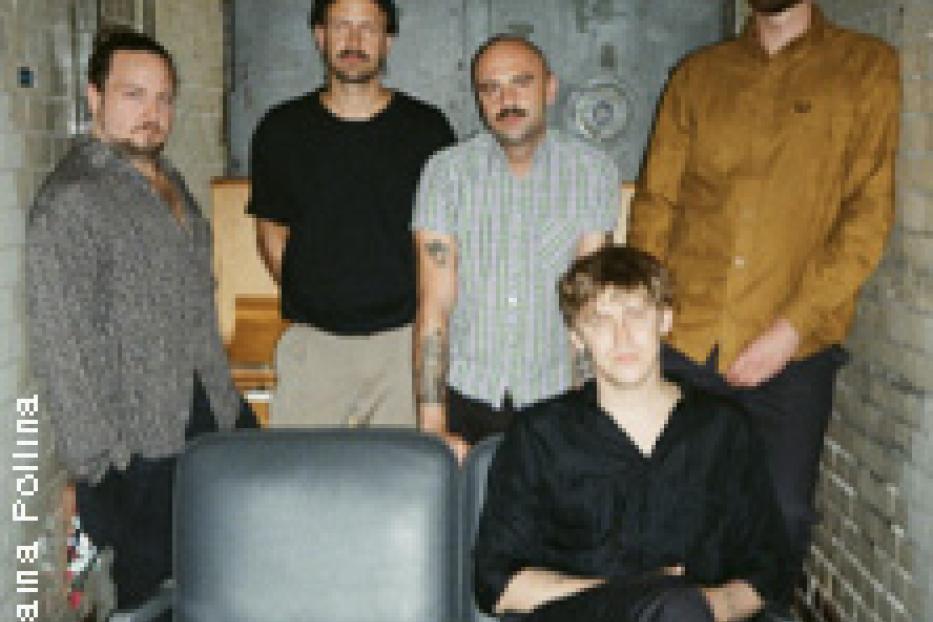 Die Band Drangsal posiert vor einer Backsteinwand und einer Metalltür.