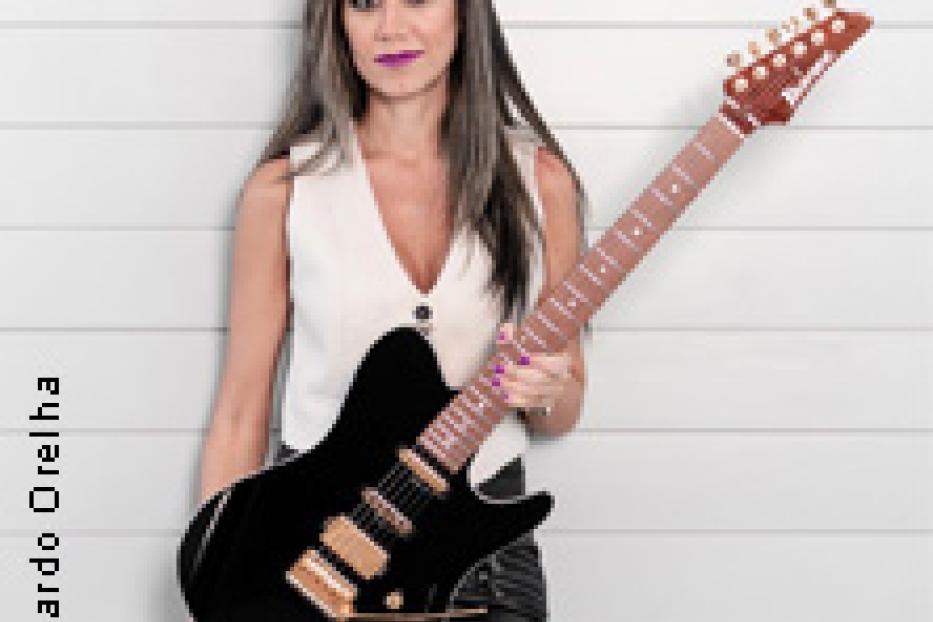 Eine Frau mit langen Haaren hält eine schwarze E-Gitarre in der Hand.