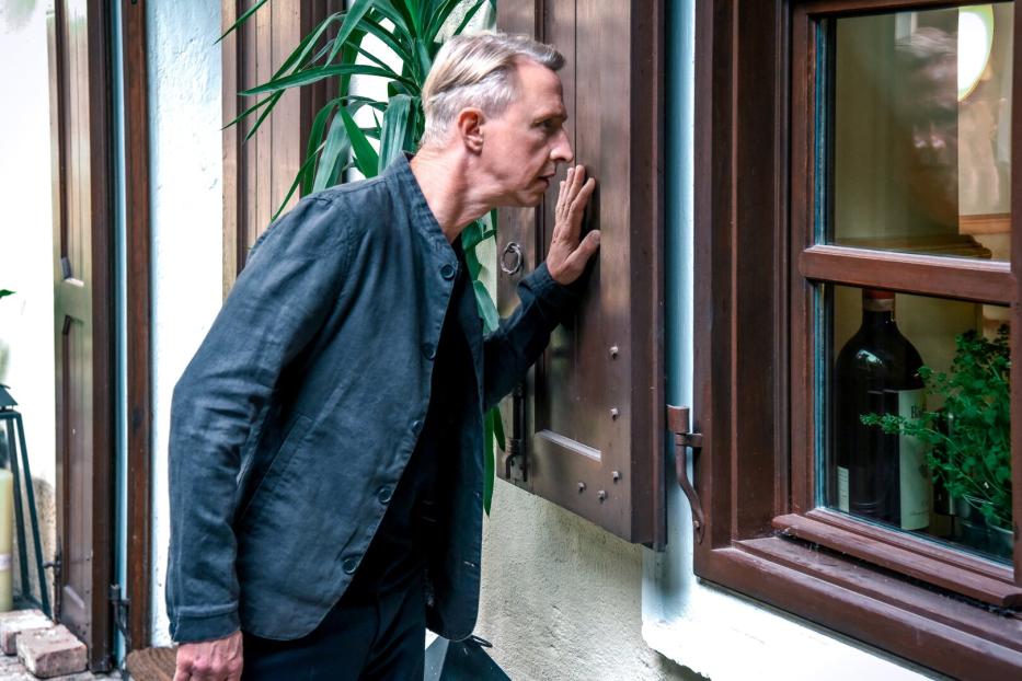 Mann blickt von außen durch ein Fenster
