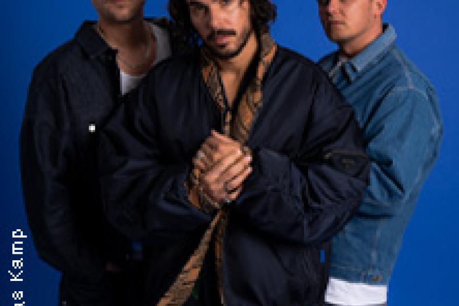 Drei Männer posieren vor einem blauen Hintergrund.