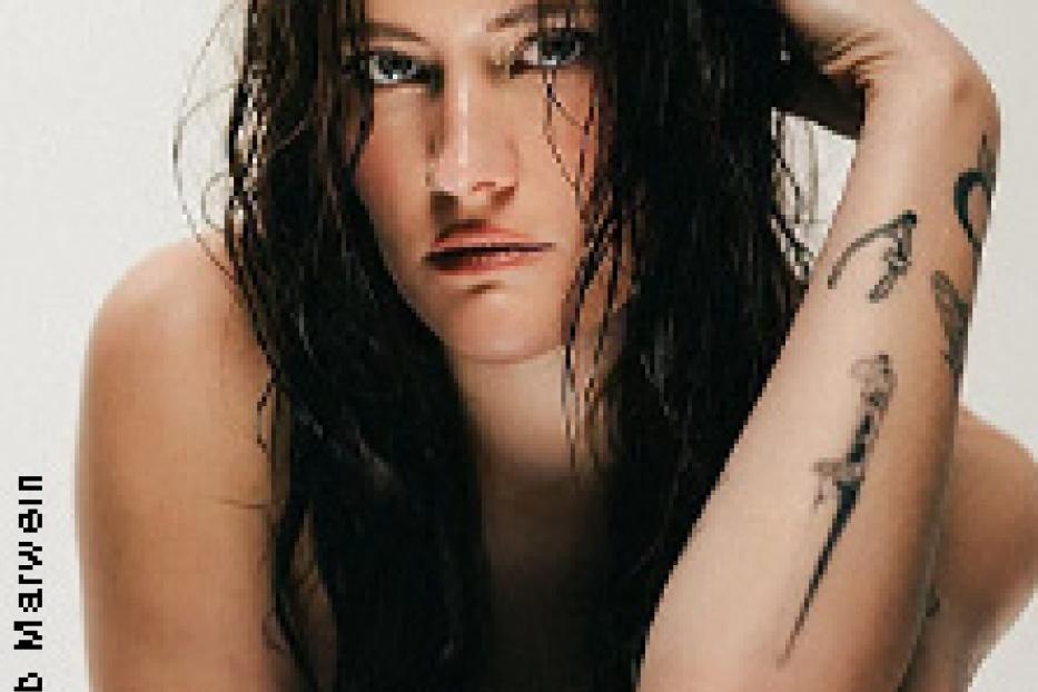 Eine Frau mit Tätowierungen posiert im Wasser.