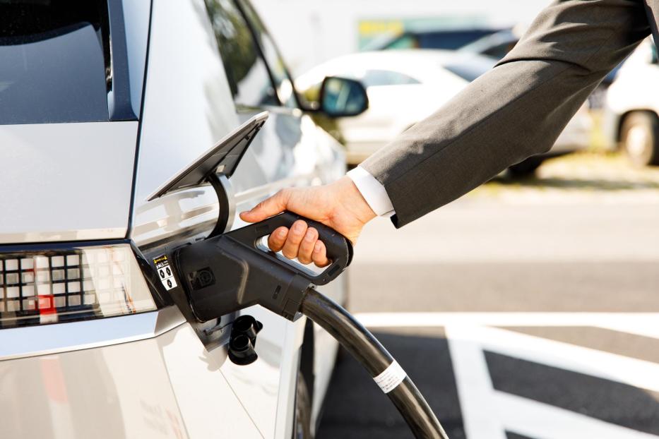 Ein Mann im Anzug lädt sein E-Auto an einer Ladestation von Wien Energie auf. 