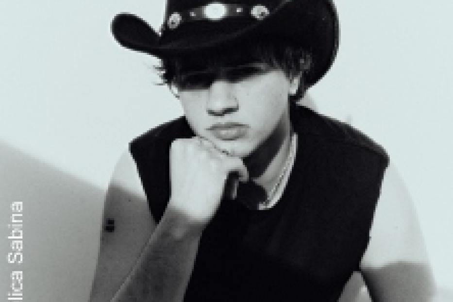 Ein junger Mann mit Cowboyhut posiert in einem schwarzen Tanktop.