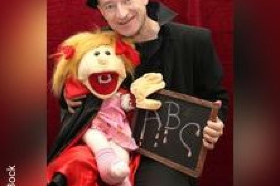 Ein Mann mit einer Puppe und einer kleinen Tafel, auf der ABC steht.
