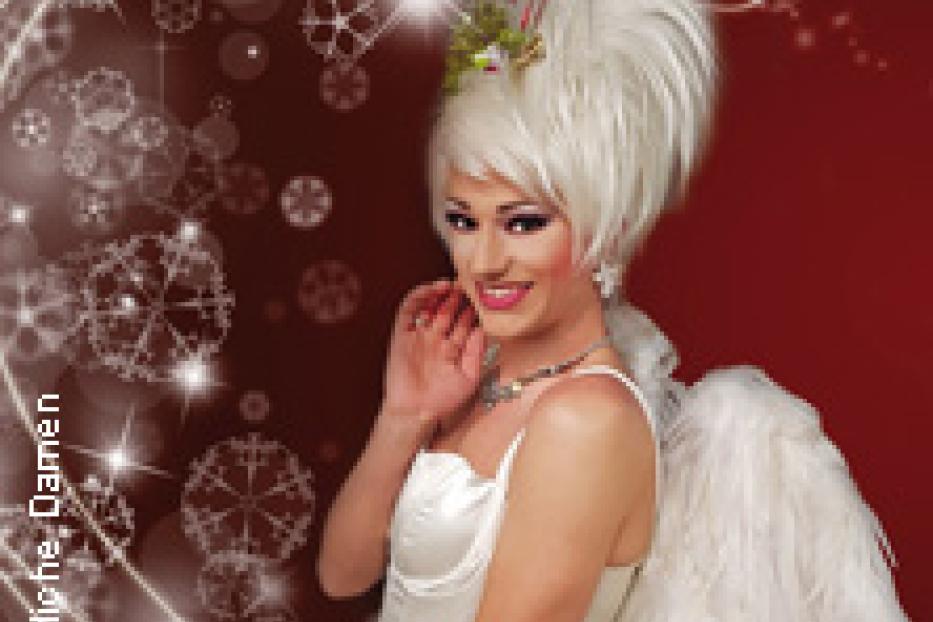 Eine Dragqueen in einem weißen Engelkostüm vor einem roten Hintergrund mit Schneeflocken.