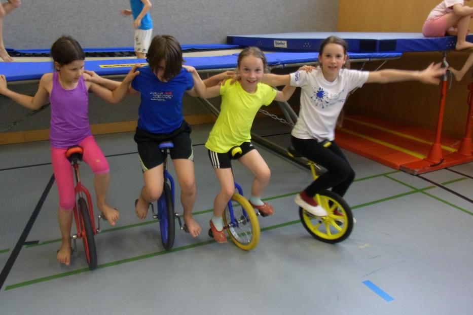 Vier Kinder auf einem Einrad.