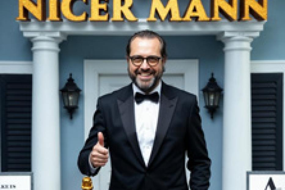 Christian Ulmen als „Alter Nicer Mann“ vor einem Hauseingang mit Säulen.