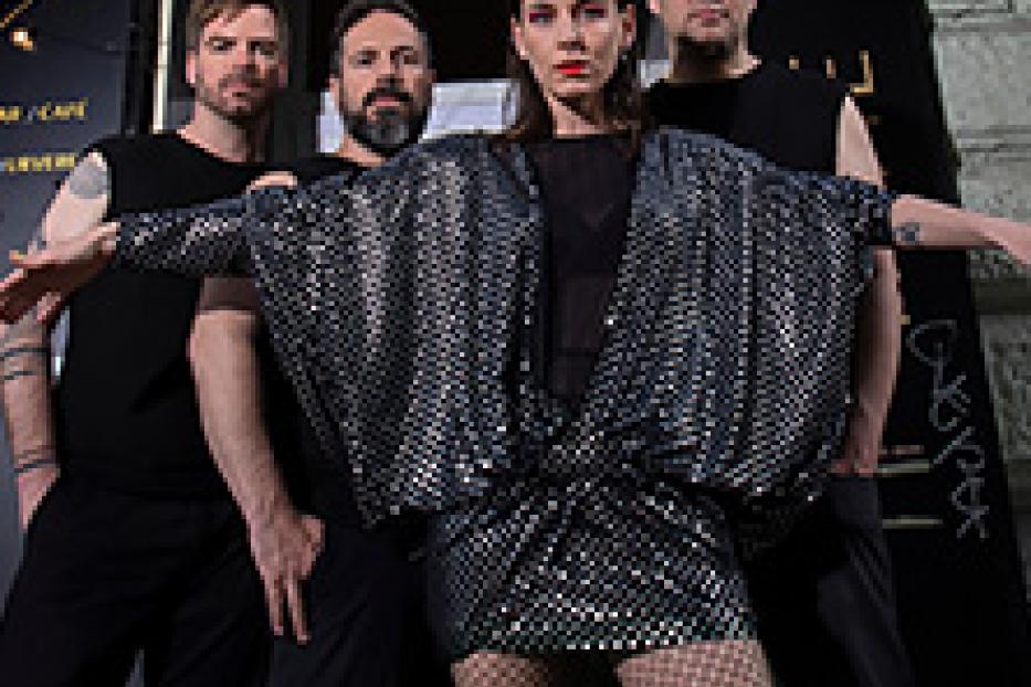 Eine Band posiert vor einem Gebäude mit einer goldenen Aufschrift.