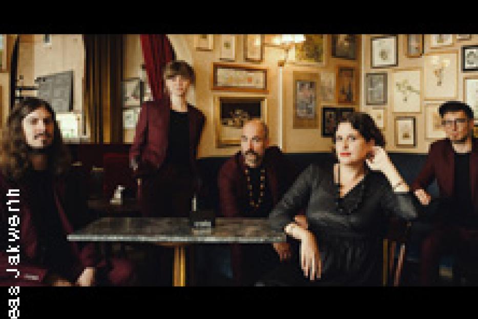 Eine Band posiert in einem Café oder einer Bar für ein Gruppenfoto.